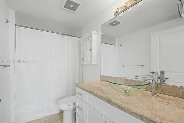 a bathroom with a granite countertop sink a toilet and shower