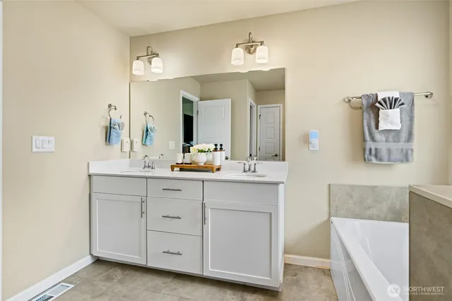 a bathroom with a double vanity sink mirror and bathtub