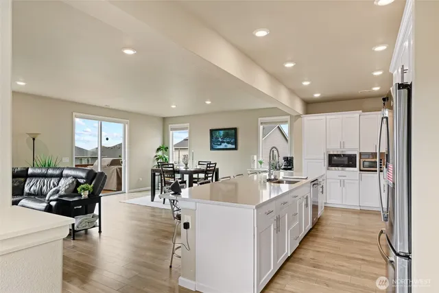 a large white dining hall with stainless steel appliances kitchen island a stove a chimney a sink and a refrigerator