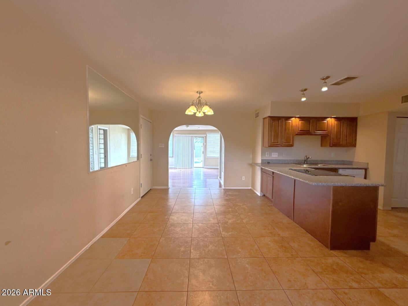 4625 South Rita Lane Tempe, AZ 85282 - Photo 3 of 16 a large kitchen with kitchen island granite countertop a stove a sink a counter space and cabinets