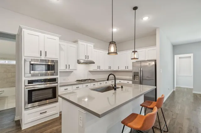 a kitchen with kitchen island a sink stainless steel appliances and white cabinets