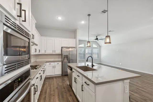 a kitchen with stainless steel appliances granite countertop a sink a stove and a refrigerator