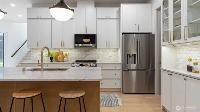 a kitchen with stainless steel appliances granite countertop a table chairs sink and cabinets