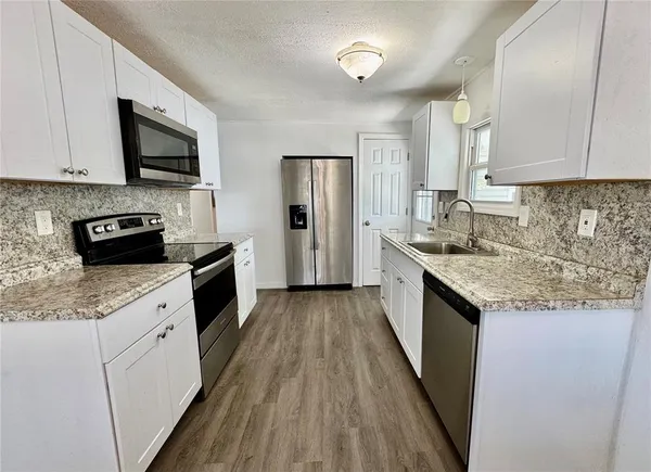 a kitchen with granite countertop a sink and steel appliances
