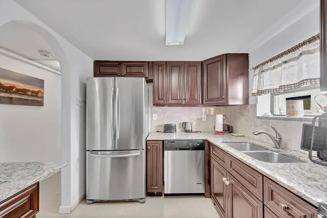 a kitchen with stainless steel appliances granite countertop a stove top oven a sink a refrigerator and dishwasher