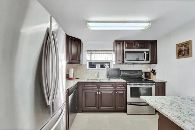 a kitchen with granite countertop cabinets stainless steel appliances and a sink