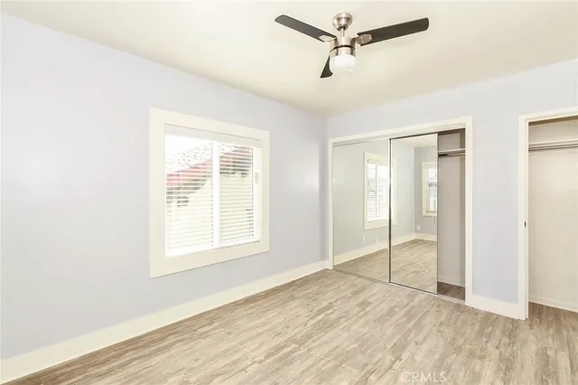 a view of an empty room with wooden floor and closet
