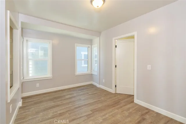 an empty room with wooden floor and ceiling fan