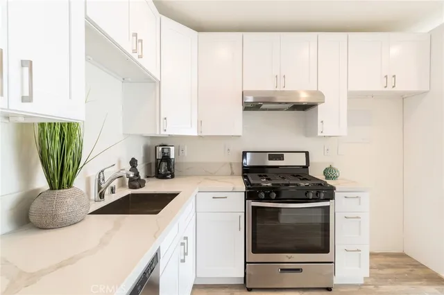 a kitchen with granite countertop a sink a stove a counter space and cabinets