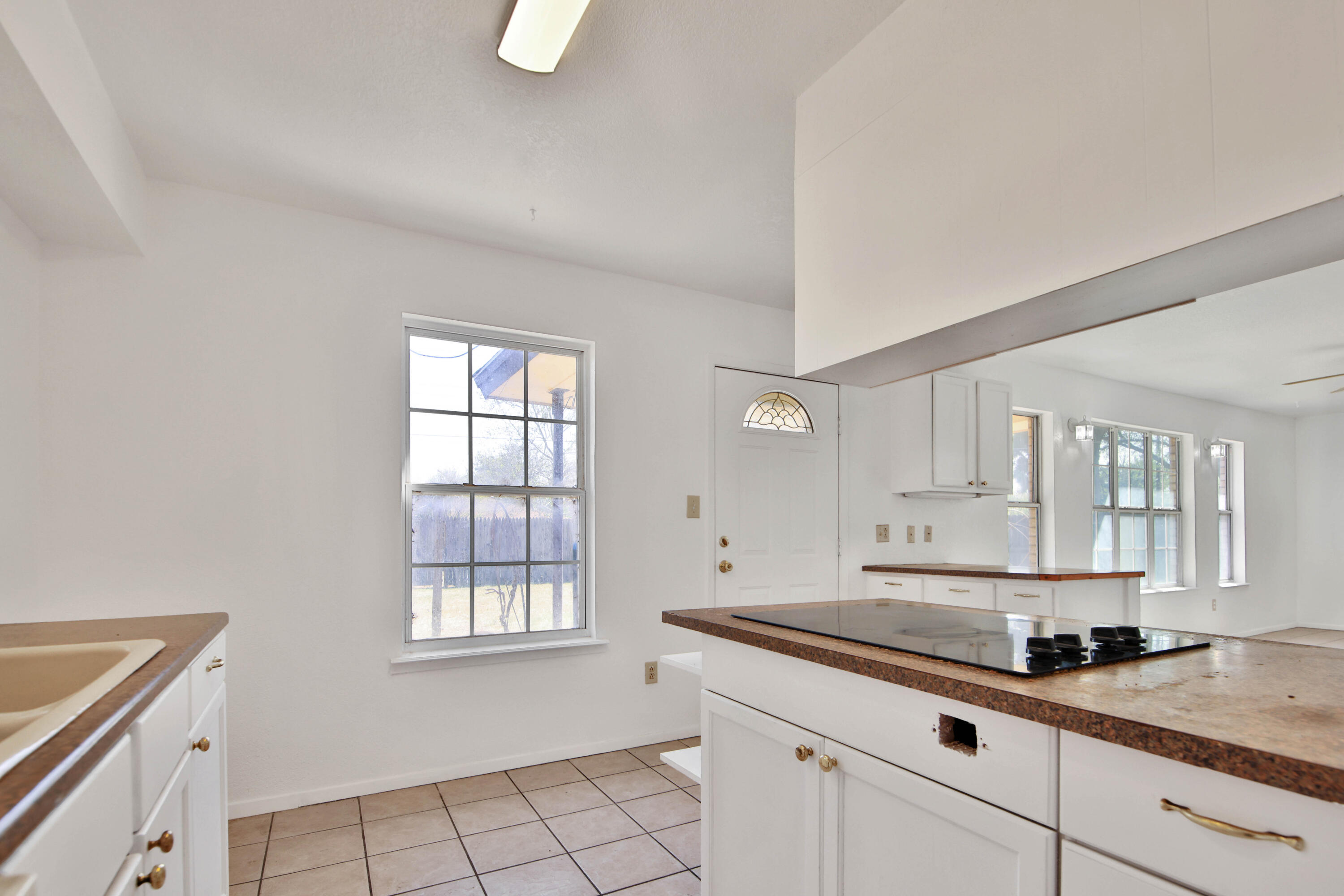 4913 56th Street Lubbock, TX 79414 - Photo 15 of 32 a kitchen with granite countertop white cabinets and a window