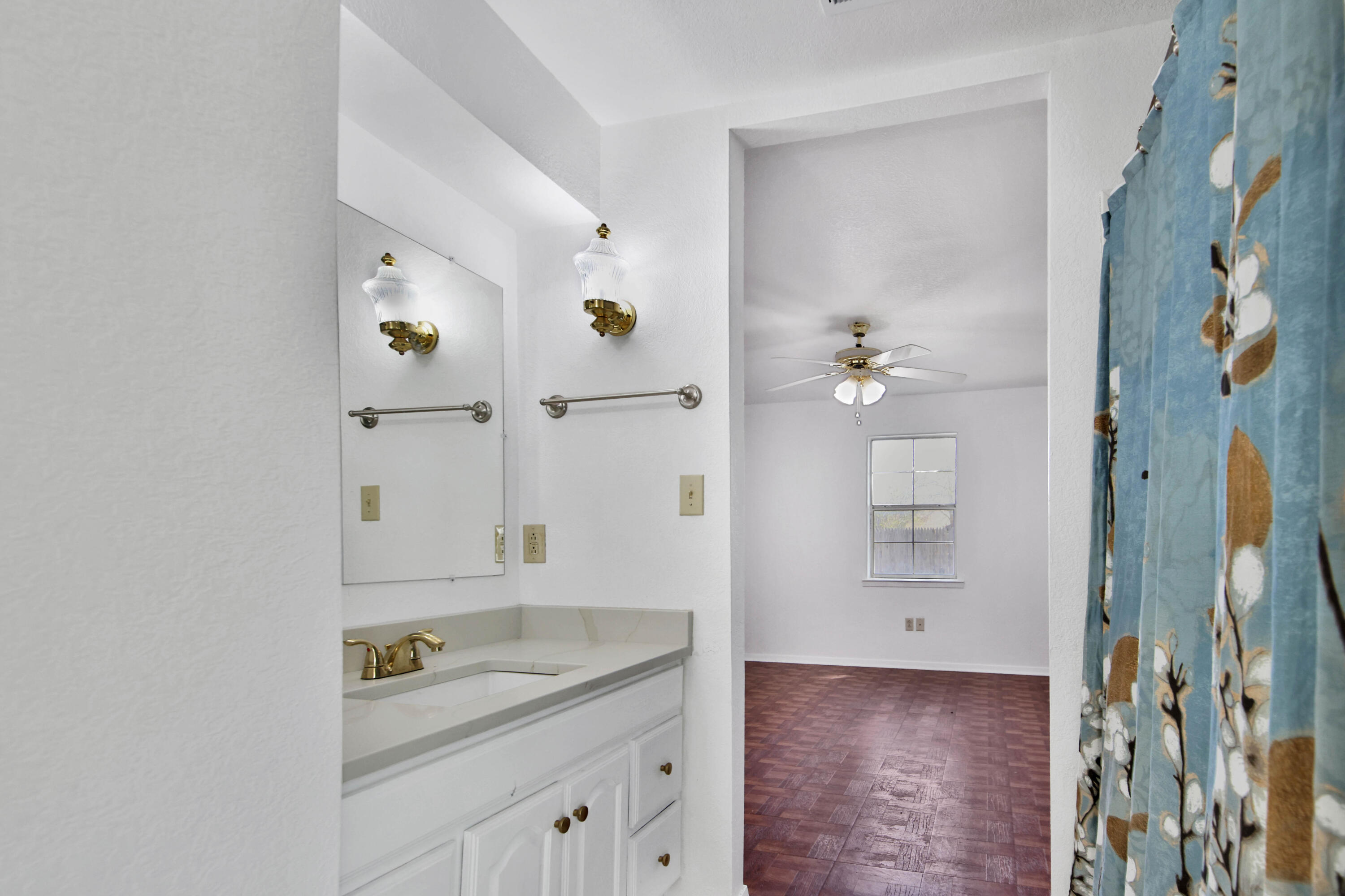 4913 56th Street Lubbock, TX 79414 - Photo 23 of 32 a bathroom with a granite countertop sink a mirror and a shower