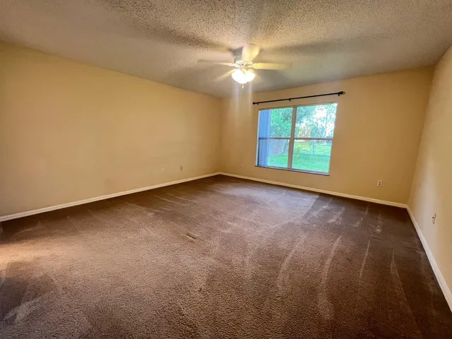 an empty room with a window and a ceiling fan