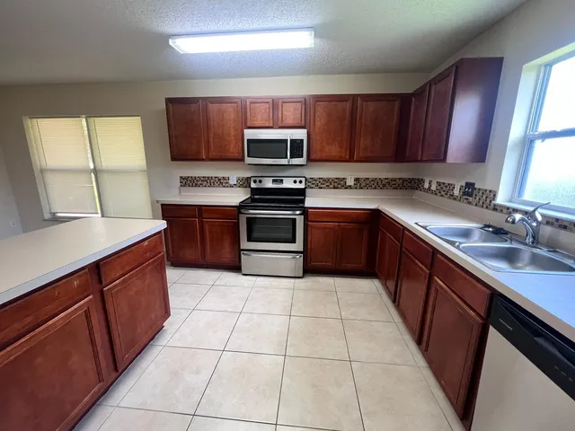 a kitchen with stainless steel appliances granite countertop wooden cabinets a stove top oven a sink and dishwasher