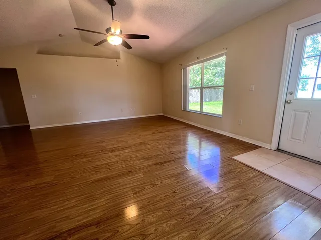 a view of an empty room with window and wooden floor