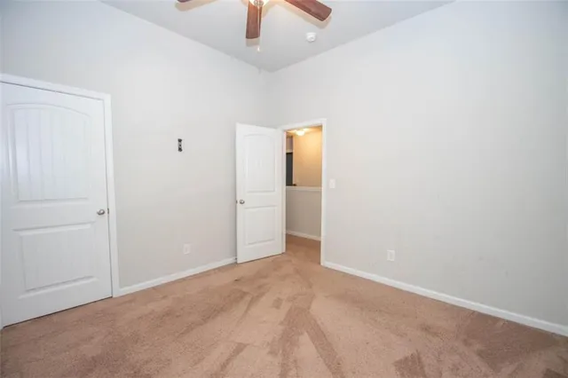 an empty room with ceiling fan and window