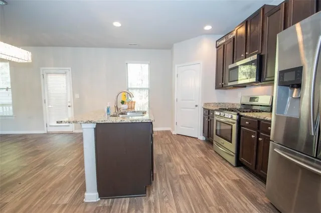 a kitchen with stainless steel appliances granite countertop a refrigerator a stove and a wooden floors