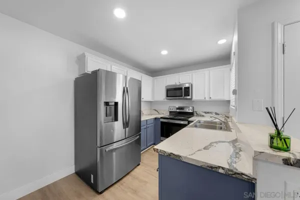 a kitchen with stainless steel appliances granite countertop a refrigerator a stove a sink a microwave and a refrigerator