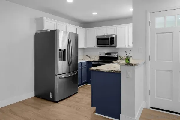 a kitchen with stainless steel appliances granite countertop a refrigerator a stove a microwave and a sink