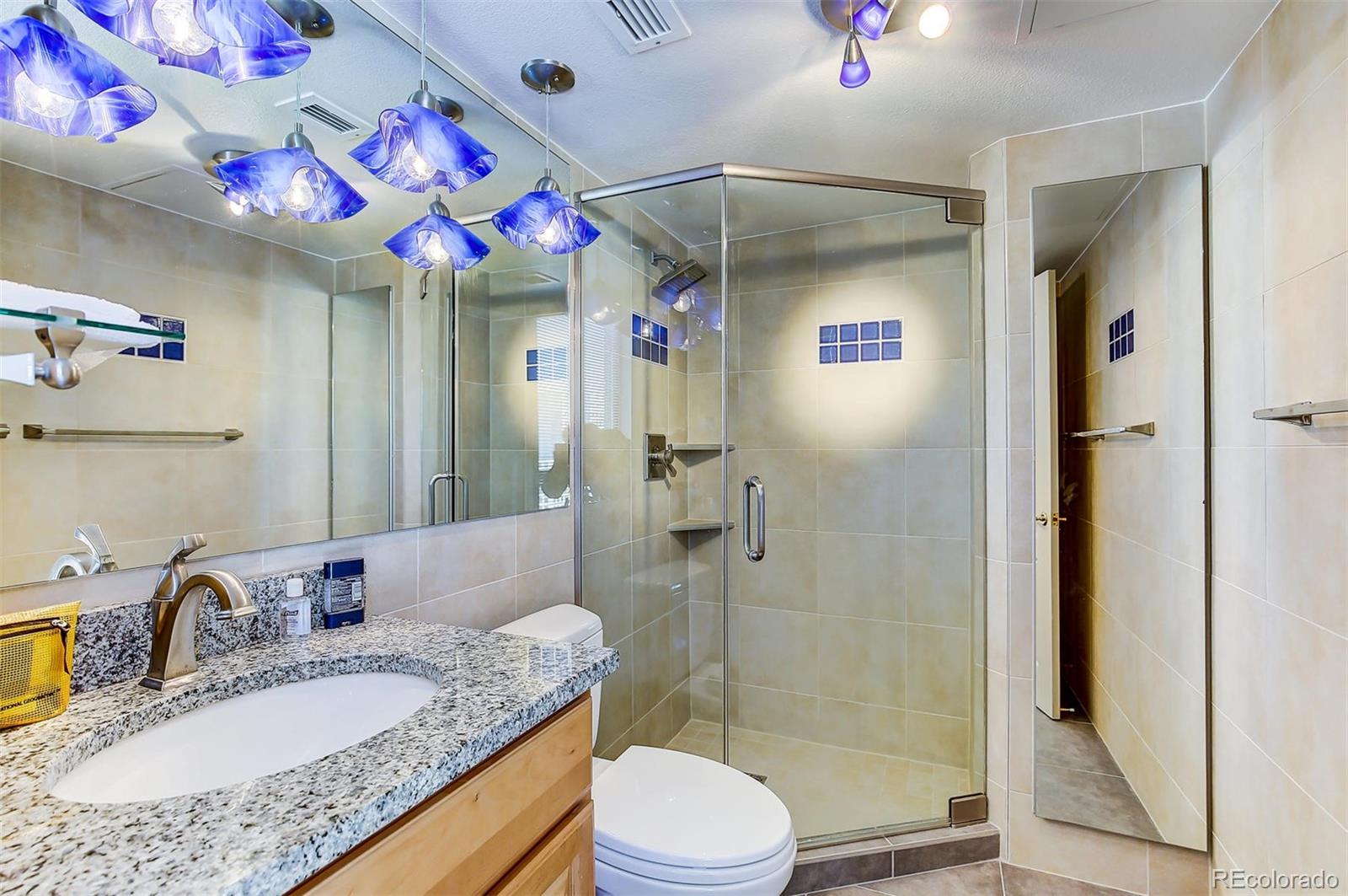 1020 15th Street, Unit 37E Denver, CO 80202 - Photo 12 of 48 a bathroom with a granite countertop sink vanity mirror bathtub shower and toilet