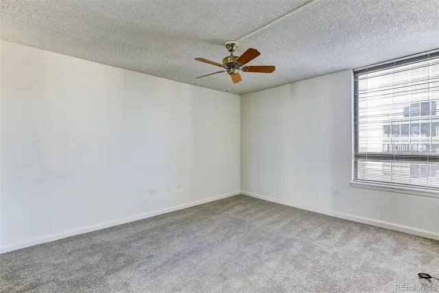an empty room with windows and fan