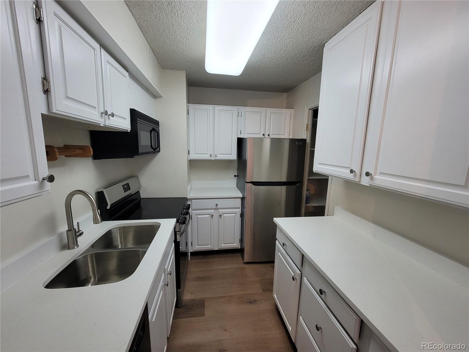 1020 15th Street, Unit 37E Denver, CO 80202 - Photo 17 of 48 a kitchen with a sink a refrigerator and cabinets