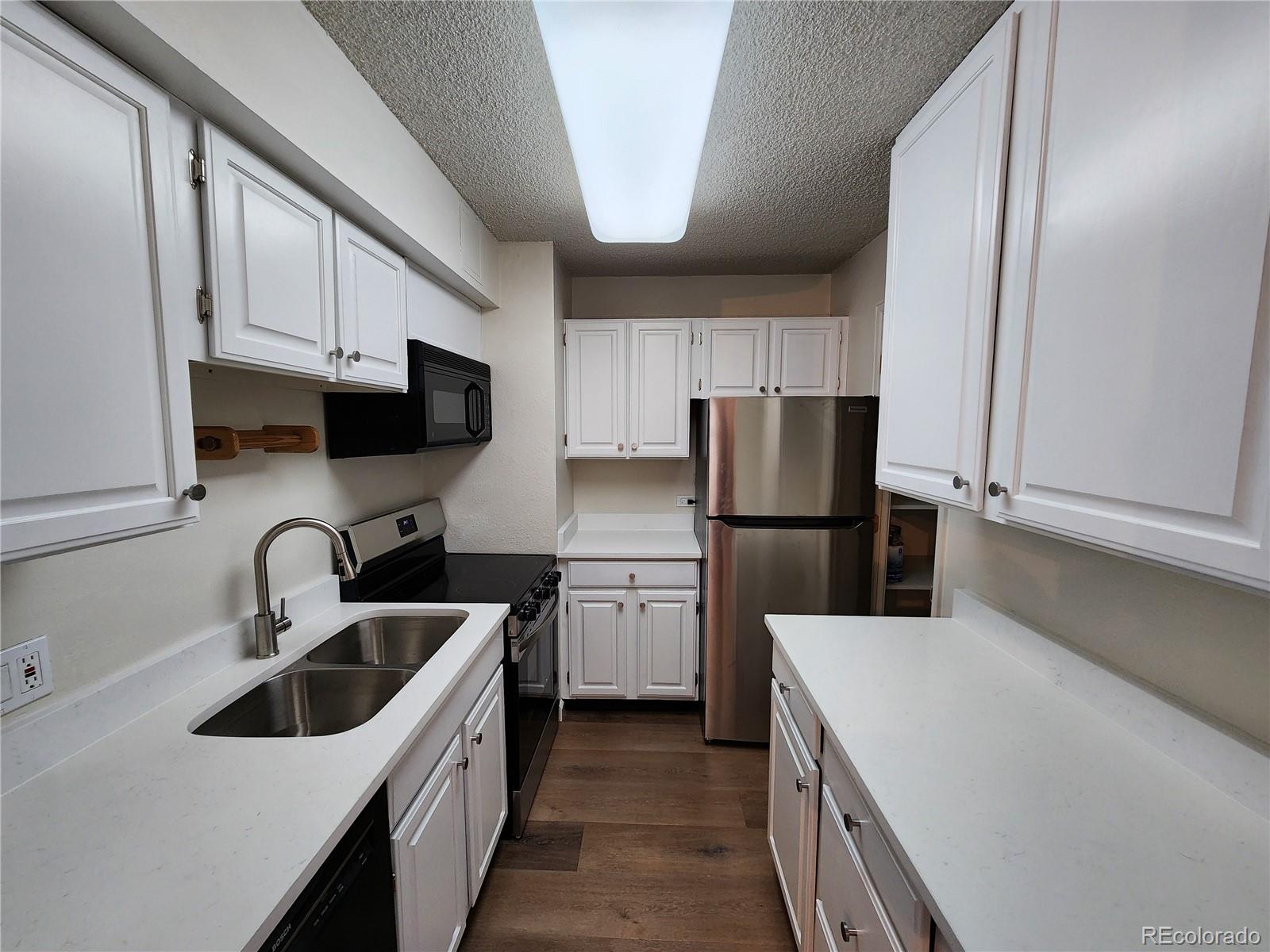 1020 15th Street, Unit 37E Denver, CO 80202 - Photo 3 of 48 a kitchen with a sink a refrigerator a microwave and cabinets