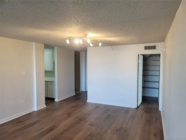 an empty room with wooden floor closet and windows
