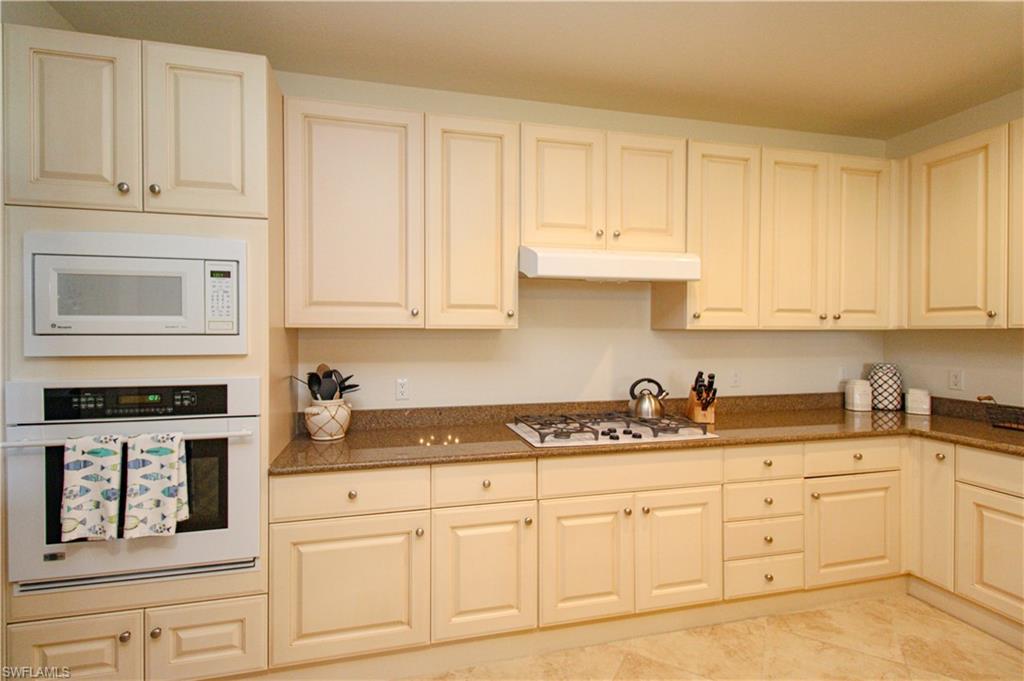 2713 Callista Court, Unit 103 Naples, FL 34114 - Photo 12 of 47 a kitchen with granite countertop white cabinets and white appliances