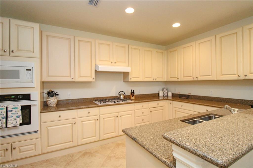 2713 Callista Court, Unit 103 Naples, FL 34114 - Photo 10 of 47 a kitchen with granite countertop white cabinets and white appliances