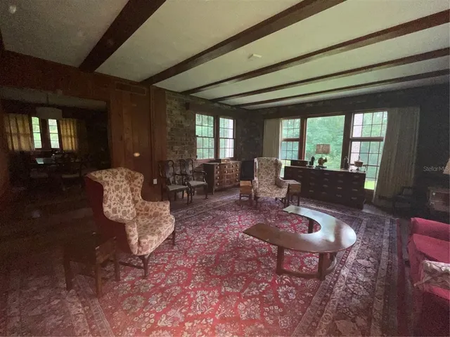 a living room with furniture couches and a dining table with wooden floor