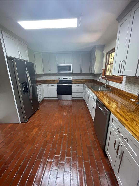 1801 Northwest 30th Terrace Gainesville, FL 32605 - Photo 19 of 36 a kitchen with stainless steel appliances granite countertop a sink a stove top oven a refrigerator with wooden floors