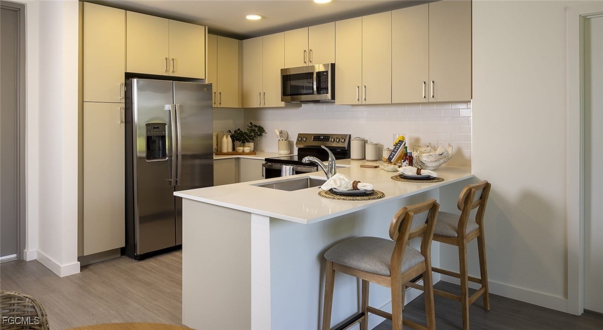 7301 Lake Bank Loop, Unit AMITY Fort Myers, FL 33966 - Photo 19 of 27 a kitchen with stainless steel appliances a table chairs microwave and refrigerator
