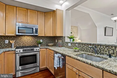 a kitchen with granite countertop a sink a stove and cabinets