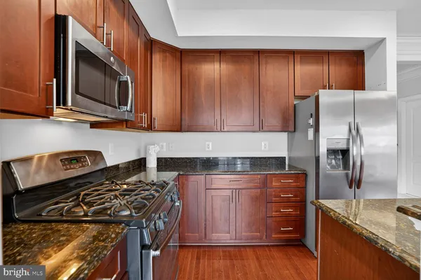 a kitchen with granite countertop a refrigerator and a stove top oven