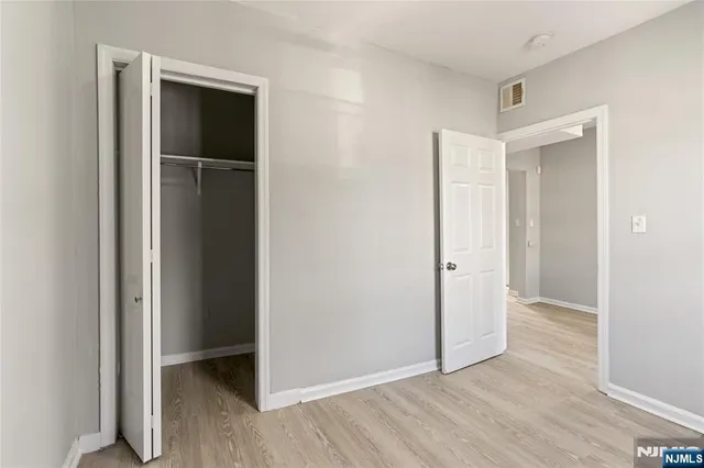 a view of an empty room with closet and a window