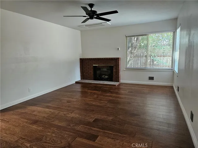 an empty room with windows fireplace and wooden floor