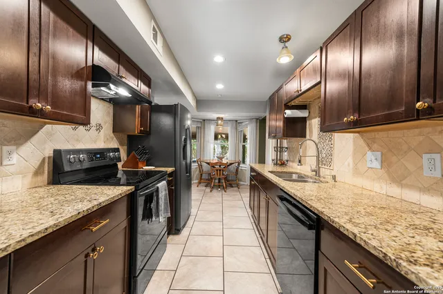 a kitchen with granite countertop stainless steel appliances a sink stove top oven and cabinets