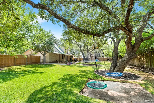 a view of a backyard with table and chairs and a large tree