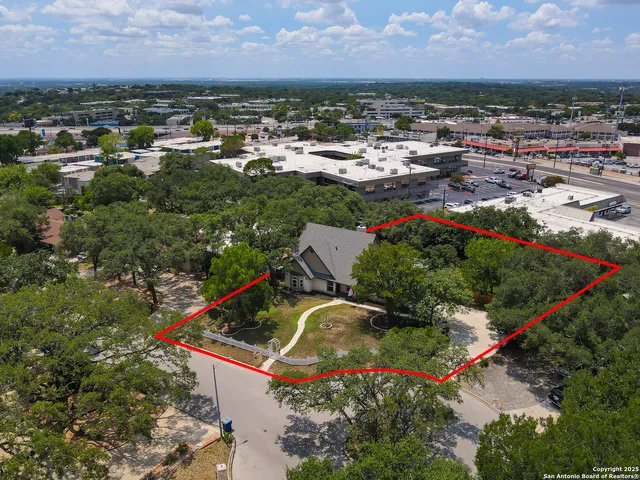 an aerial view of residential houses with outdoor space and trees