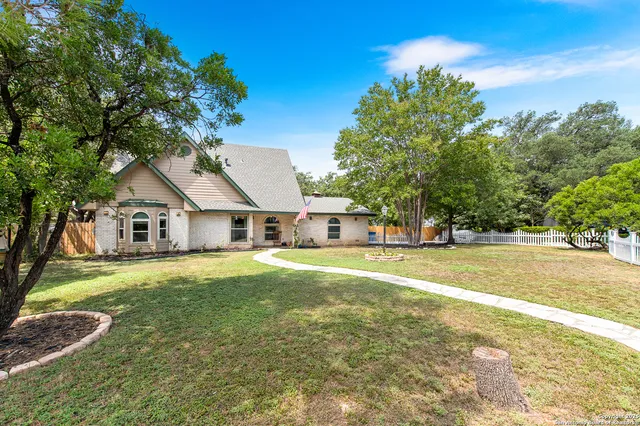 a front view of a house with a garden and trees