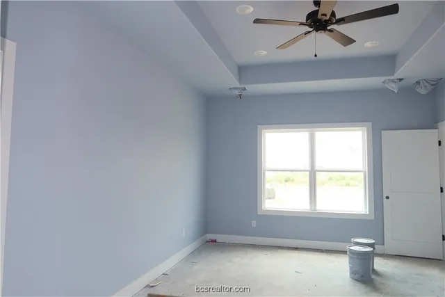 an empty room with a window and a ceiling fan