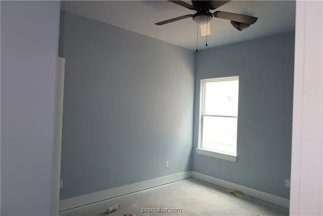 an empty room with a window and a fan