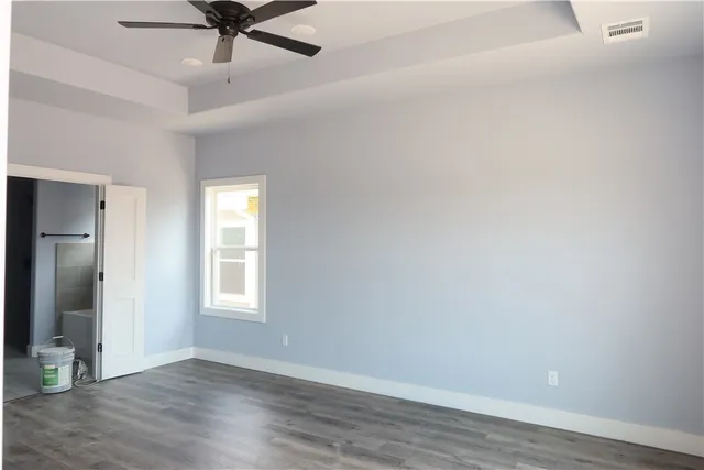 an empty room with wooden floor fan and windows
