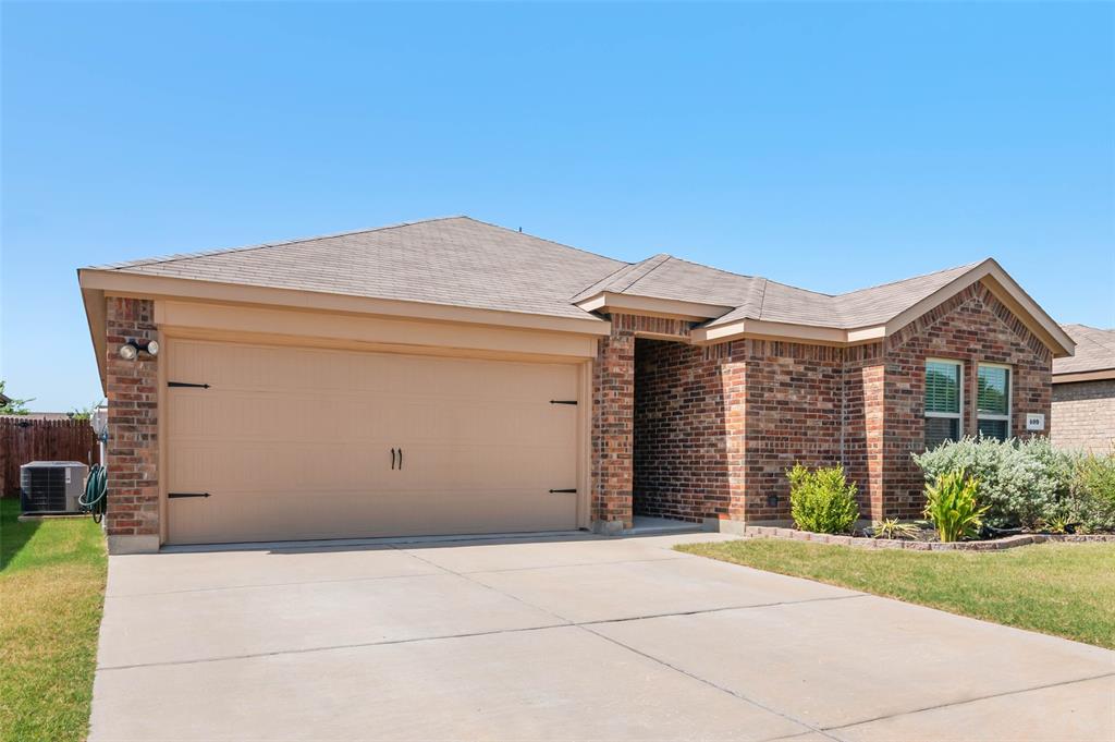 409 Wilson Way Denton, TX 76207 - Photo 30 of 33 Brick exterior with a beige garage door, concrete driveway, and front landscaping