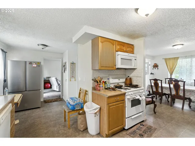 a living room with stainless steel appliances furniture a rug and a kitchen view