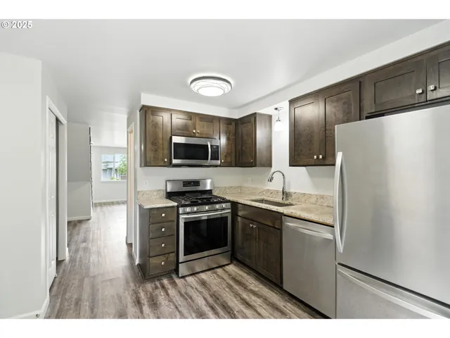 a kitchen with stainless steel appliances granite countertop a refrigerator a stove top oven a sink and dishwasher