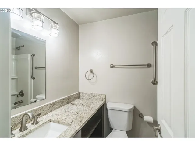 a bathroom with a granite countertop sink mirror vanity and toilet