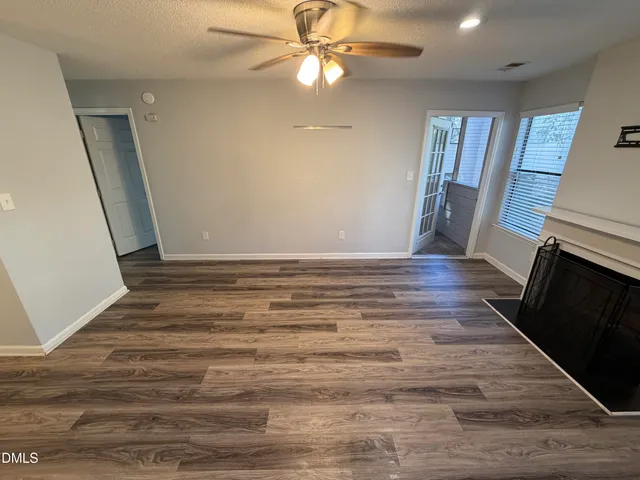 a view of an empty room with wooden floor and a fireplace
