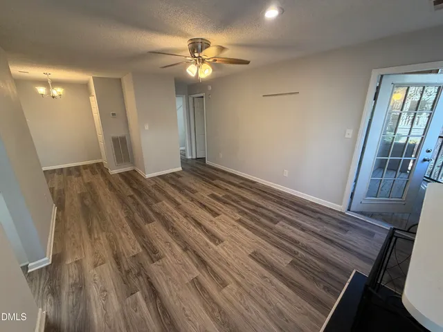 a view of an empty room with wooden floor and a chandelier