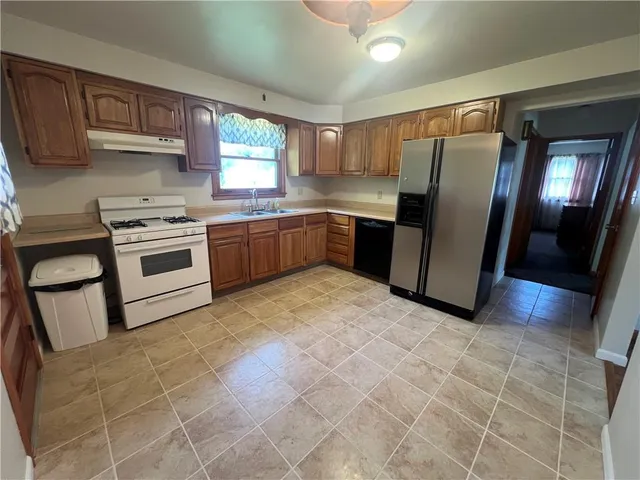 a kitchen with stainless steel appliances granite countertop a stove a sink dishwasher a refrigerator and cabinets with wooden floor